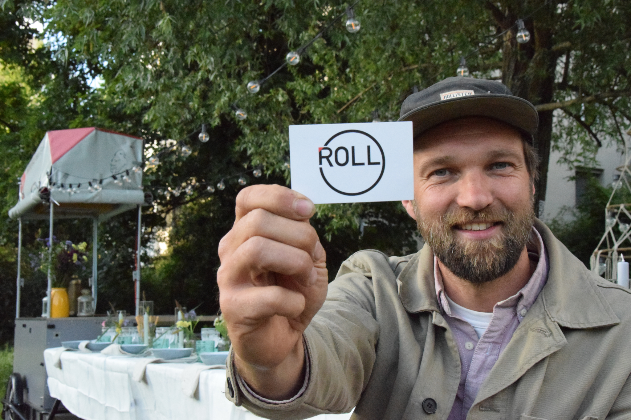 Ruben Lagies mit einer Visitenkarte von LIVIN'ROLL an der Fahrradtafel in Charlottenburg