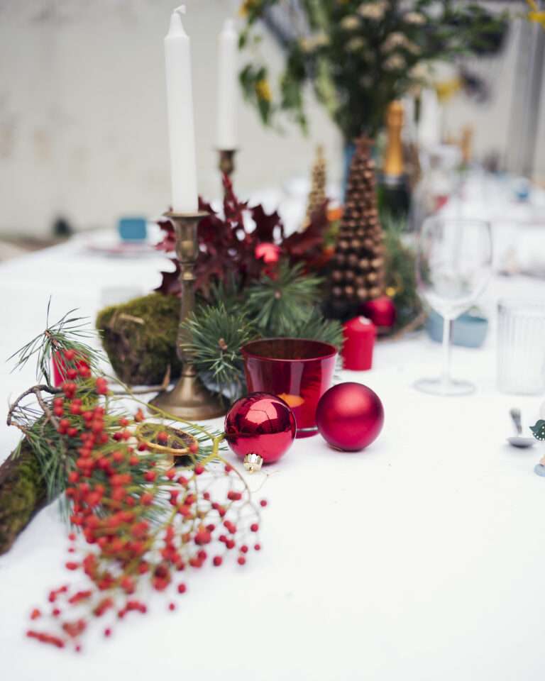 Winterliche Tischdeko mit Tannenzweigen, Kerzen, Äpfeln und Laternen auf der langen Tafel