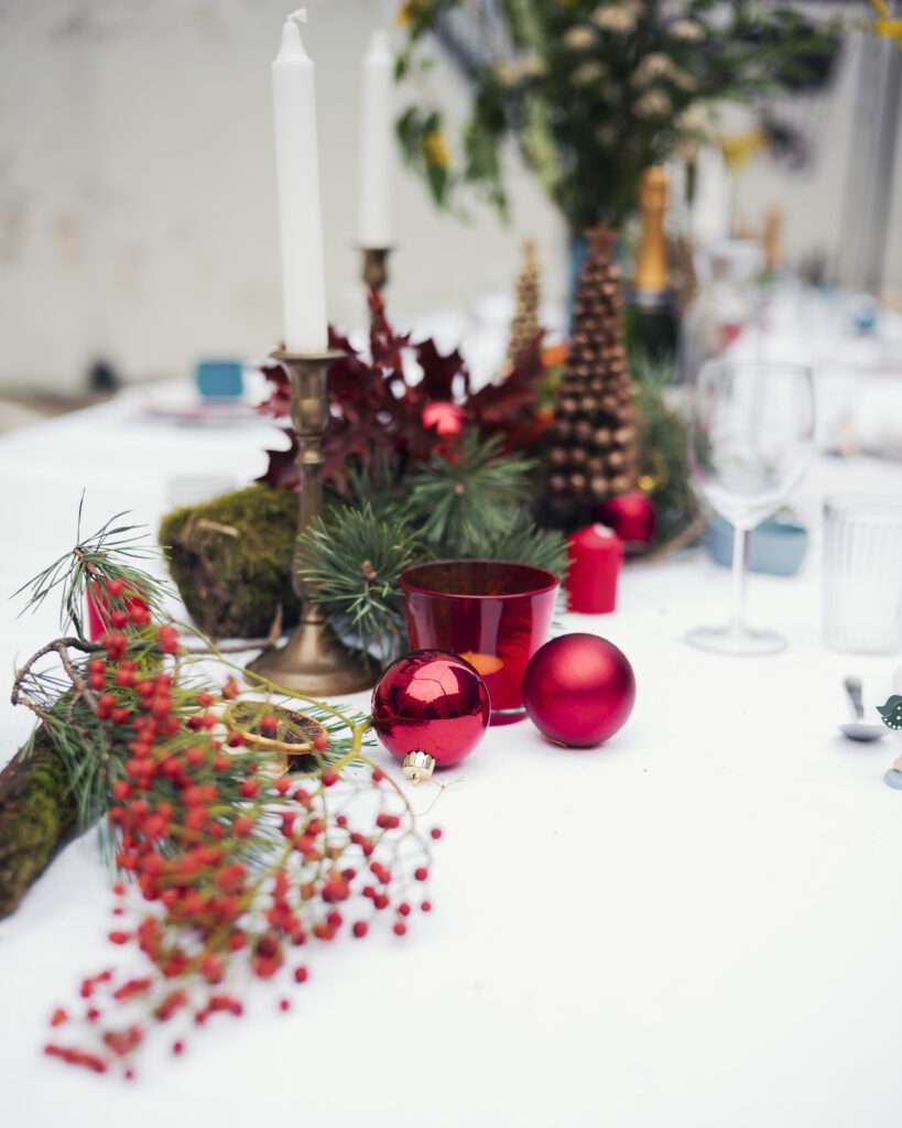 Winterliche Tischdeko mit Tannenzweigen, Kerzen, Äpfeln und Laternen auf der langen Tafel